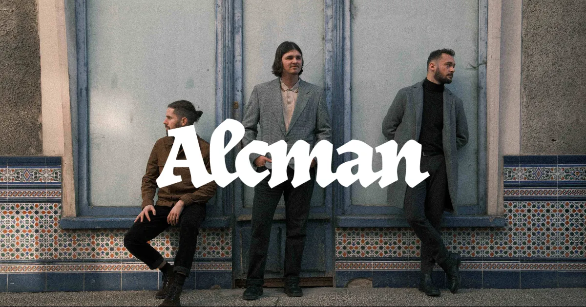 The three band members posing front of a textured wall, the logo is prominently overlaid in white, stylized text in the center of the image.